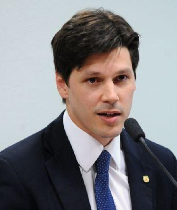 Ein Mann im Anzug und Krawatte spricht vor einer Wand in ein Mikrofon, wahrscheinlich zur Ankündigung eines vom Staat genehmigten Gesetzes, das den Internetgebrauch verbietet.