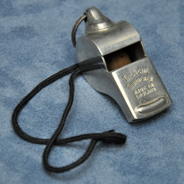 Metallpfiff mit schwarzer Schnur auf blauer Oberfläche, mit eingraviertem Text.