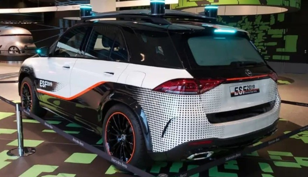 Mercedes-Benz E-Klasse Electric SUV auf der IAA in Frankfurt zu sehen, umgeben von Absperrpollern mit Seilen und Lichtern, mit einem weiteren Fahrzeug und Text an der Wand im Hintergrund.