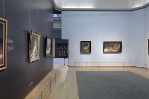 Ein prächtiger Raum in der Nationalgalerie von London, gefüllt mit zahlreichen Gemälden an den Wänden, Teppichboden, Geländern und einer Decke mit Beleuchtung.