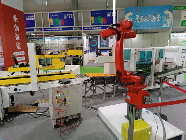 Gruppe von Robotern auf einem Tisch in einer Fabrikumgebung mit Maschinen, Kabeln, Leiterplatten und Menschen im Hintergrund.