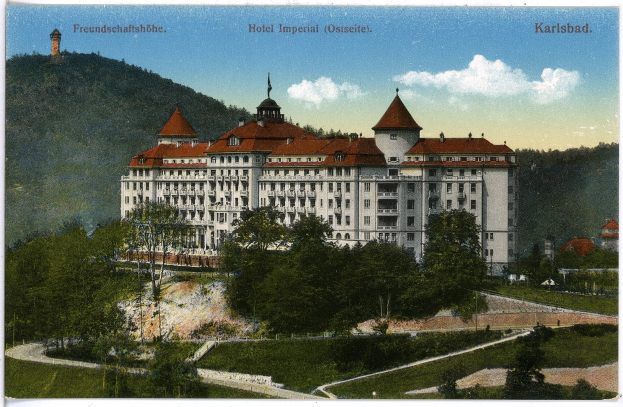 Alte Ansichtskarte des Hotels Imperial in Karlsbad, Deutschland, mit einem großen Gebäude mit Fenstern, umgeben von Bäumen, Pflanzen, Gras, einem Weg, einer Baumgruppe, Hügeln und einem bewölkten Himmel, mit Text oben.