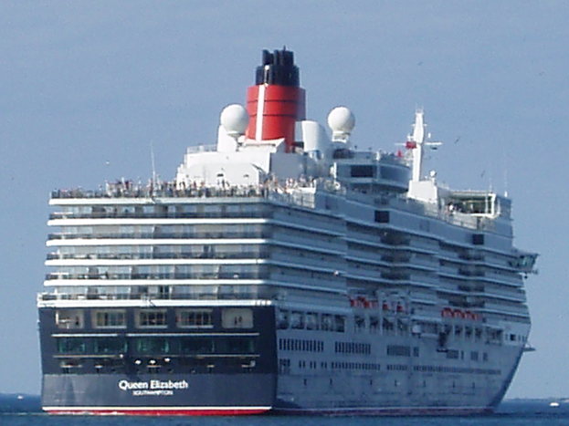 Großes Kreuzfahrtschiff Queen Elizabeth auf hoher See mit anderen Booten im Hintergrund und einem klaren blauen Himmel.