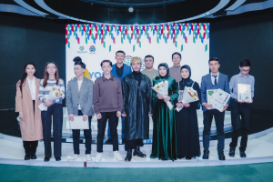 Gruppe von Menschen auf einer Bühne mit Blumensträuseln und Urkunden, mit einem "Jugend Solar Awards 2019"-Plakat im Hintergrund.