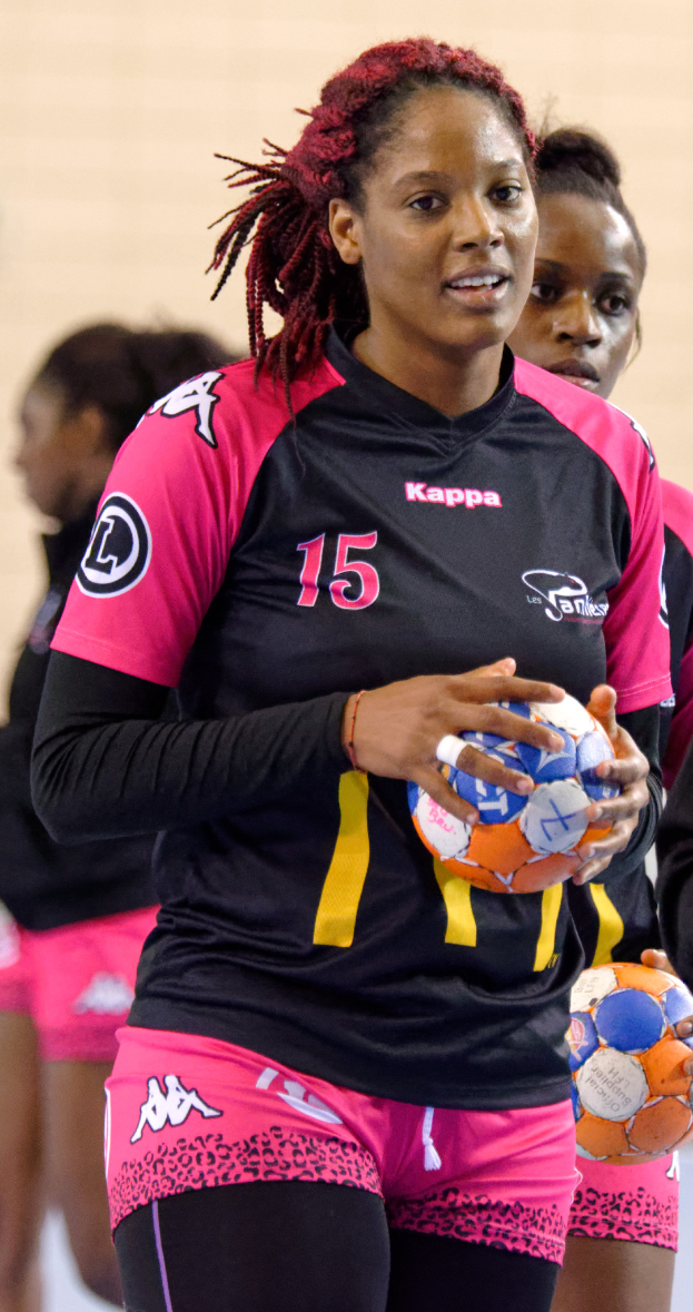 Eine Gruppe von Frauen, die zusammenstehen und jeweils einen Fußball halten, wobei die mittlere Frau ein menschliches Gesicht hat und direkt in die Kamera schaut, trägt ein weißes T-Shirt und blaue Shorts.