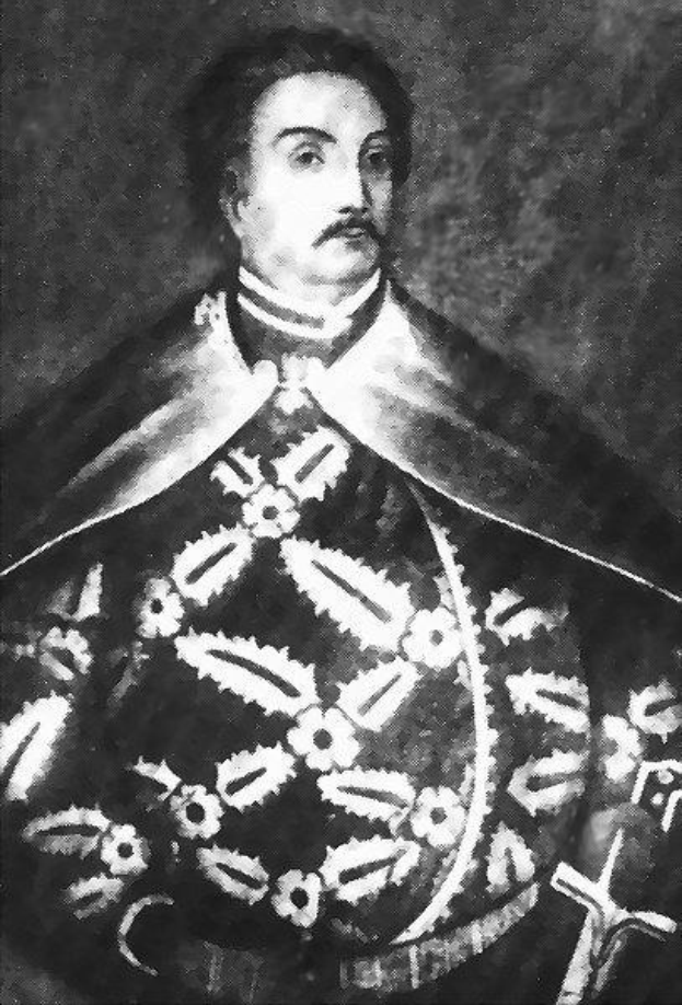Schwarzes und weißes Foto von Papst Johannes Paul II. in Priesterkleidung, der eine schwarze Robe mit weißem Kragen und Manschetten trägt und die Hände gefaltet hat, mit ernstem Gesichtsausdruck und direktem Blick.