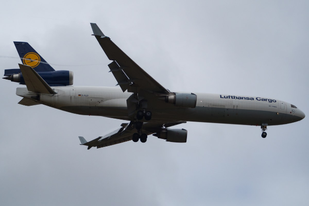 Lufthansa Cargo Boeing 777-300ER im Flug gegen einen bewölkten Himmel, mit sichtbarem Text auf dem Rumpf.