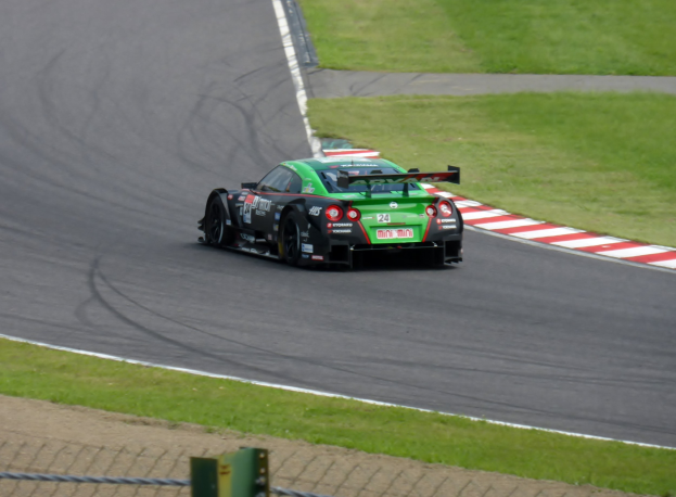 Ein Nissan GT-R Nismo GT3-Rennwagen auf der Nürburgring 24 Stunden-Strecke, umgeben von grünem Gras und einem Zaun unten.