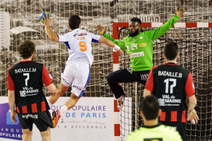 Eine Gruppe von Männern, die Handball spielen, mit einem, der springt und den Ball hält, vor einem Torpfosten und einem Banner "Ligue 1 - Bordeaux vs Marseille".