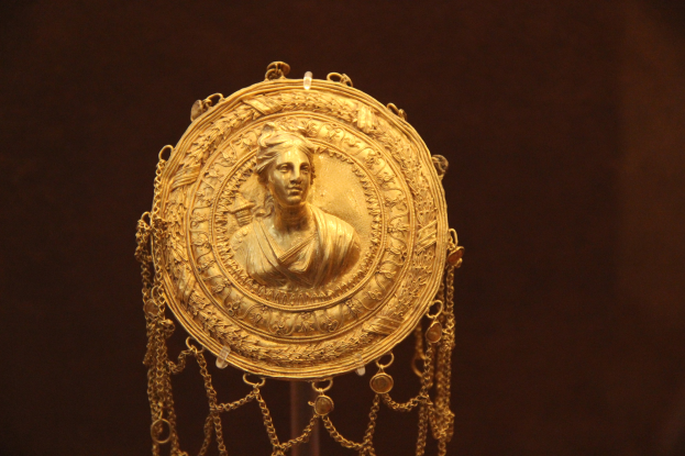 Goldener Medaillon mit einer Frauengestalt auf dunklem Hintergrund, mit feiner und luxuriöser Verzierung.