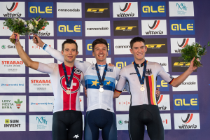 Drei Männer stehen auf einem Podium, jeder trägt eine Medaille und hält einen Blumenstrauß, im Hintergrund ist ein "Giro d'Italia"-Schild zu sehen.