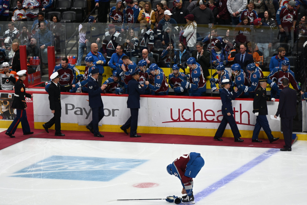 Ein Eishockeyspieler auf dem Eis umgeben von Teamkollegen und Gegnern, mit Zuschauern im Hintergrund während eines Spiels von Colorado Avalanche gegen San Jose Sharks am 24. März 2015.