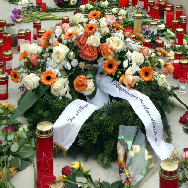 Gedenkstätte in Berlin mit Blumen und Kerzen vor einer Wand aufgestellt