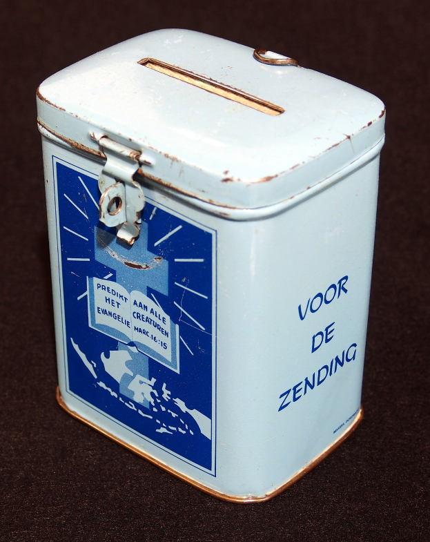 Weißer und blauer Blechspartopf mit einem blauen und weißen Schild, das "Voor de Zending" darauf steht, auf einer schwarzen Oberfläche.