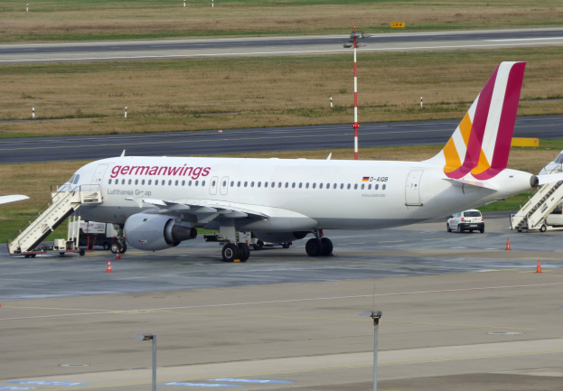 Germanwings Airbus A320-200 auf dem Frankfurter Flughafen mit Bodenfahrzeugen, Verkehrskegeln, Pfählen und Gras im Hintergrund.