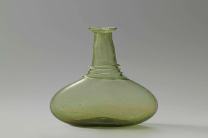 Ein grüner Glasweinkelch mit Verschluss, zylindrischer Form, breiter Basis, engem Hals und kunstvollen Verzierungen, mit glänzender Oberfläche.