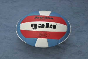 Ein blauer und roter Volleyball mit dem Wort "Gala" darauf, der auf einer blauen Oberfläche sitzt.