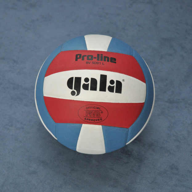 Ein blauer und roter Volleyball mit dem Wort "Gala" darauf, der auf einer blauen Oberfläche sitzt.