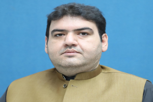 Ein Mann in einer braunen Weste und schwarzem Hemd steht vor einem blauen Hintergrund und sieht verzweifelt und hoffnungslos aus, wahrscheinlich wegen einer lebenslangen Haftstrafe.