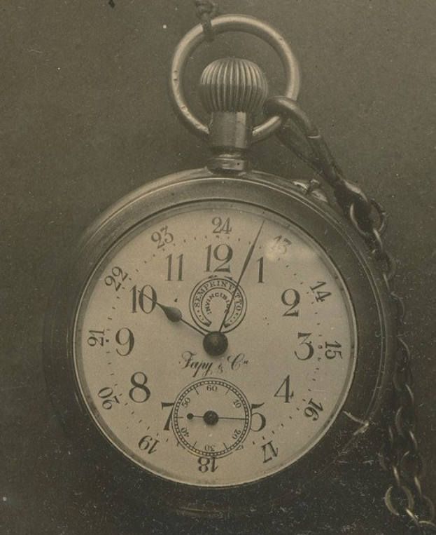 Ein Schwarz-Weiß-Foto eines alten Taschenuhr mit einer Kette, das eine nummerierte Zifferblatt zeigt.