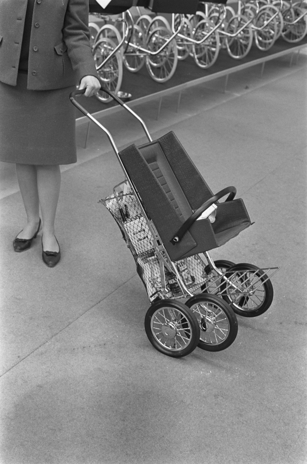 Frau mit Einkaufswagen in einem Laden mit Fahrrädern im Hintergrund, Bild in Schwarz-Weiß.