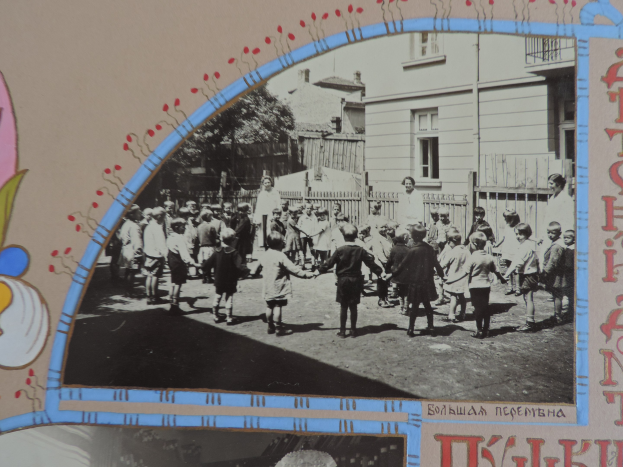 Schwarz-weißes Foto von Kindern, die in einer Straße spielen, umgeben von Gebäuden, Bäumen und einem Zaun.