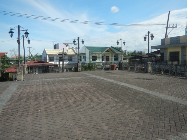 Leeres Stadtparkhaus umgeben von Gebäuden, Straßenmöblierung und Bäumen unter einem bewölkten Himmel.