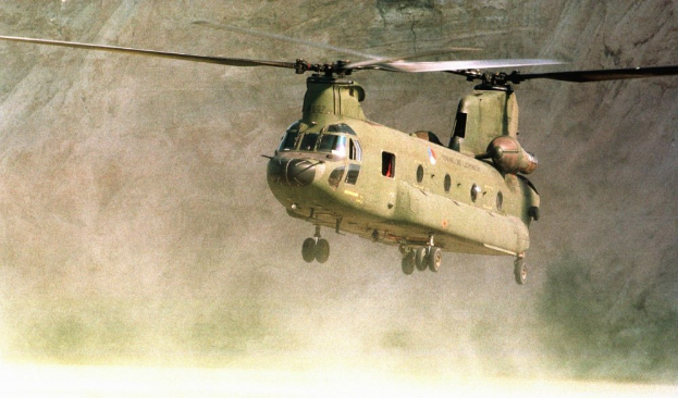 Ein Militärhelikopter fliegt durch die Luft mit einem Berg im Hintergrund.