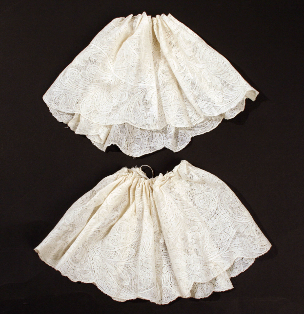 Zwei weiße Spitze-Minis mit zarten Mustern auf schwarzem Hintergrund.