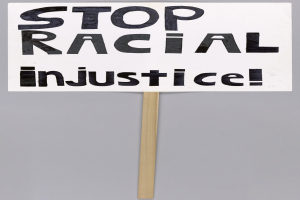 Ein weißes Schild mit schwarzer Schrift, die 'Stop Racial Injustice' lautet.