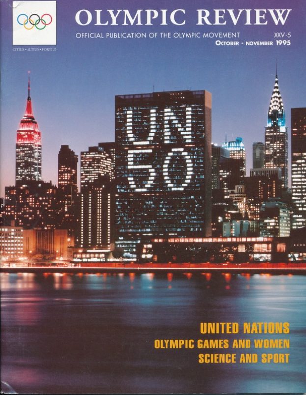 Ein Buch mit dem Titel "Olympic Review Official Publication of the Olympic Movement" liegt auf einer flachen Oberfläche, mit einer Stadtansicht mit Gebäuden, Lichtern und Wasser auf dem Cover, mit dem Text "United Nations Olympic Games and Women Science and Sport" zu sehen.