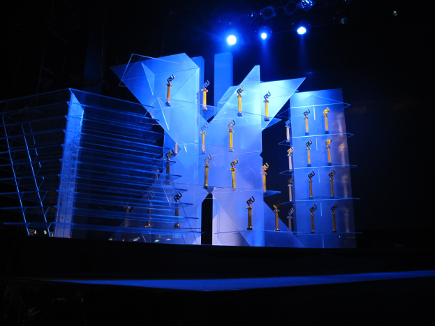 Bühne für eine Preisverleihung mit dunklem Hintergrund und minimaler Beleuchtung, die nur wenige Gegenstände auf der Bühne zeigt.