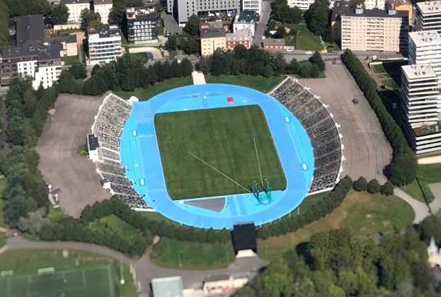 Luftbild des Olympiastadions in München, Deutschland, umgeben von Stadtgebäuden, Bäumen, Straßen, Fahrzeugen und Gras.