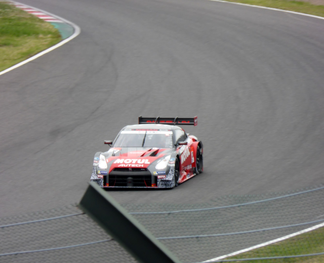 Ein Nissan GT-R Nismo GT3 Rennauto auf der Nürburgring 24 Stunden Rennstrecke, umgeben von grünem Gras auf beiden Seiten.